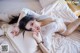 A woman laying on top of a bed in a white shirt.