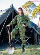 A woman in a military uniform holding a shovel.