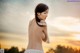 A woman in a white lingerie standing in front of a sunset.