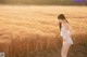 A woman in a white dress standing in a field.