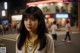 A woman standing in the middle of a city street at night.