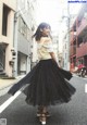 A woman in a black tulle skirt is walking down the street.