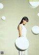 A woman in a white dress standing in front of white spheres.