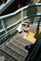 A woman is sitting on the steps of an escalator.