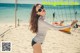 A woman in a bikini playing volleyball on the beach.