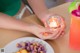 A person holding a candle in their hands next to a plate of food.