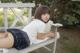 A woman laying on a wooden bench in a park.